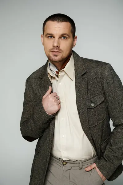 Man in tweed jacket, white shirt, and scarf poses with hand in pocket. — Stock Photo