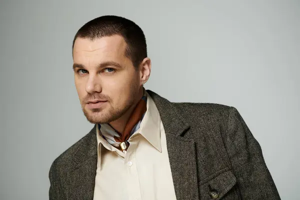 A man in a stylish herringbone blazer and white shirt looks directly at the camera. — Stock Photo