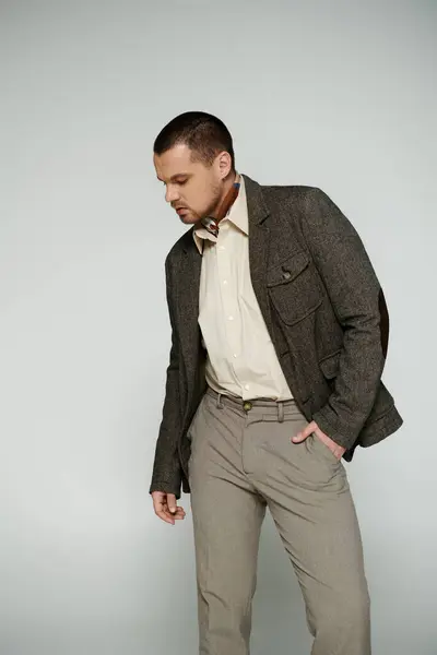 A stylish man in a brown jacket and khaki pants poses against a plain white background. — Stock Photo