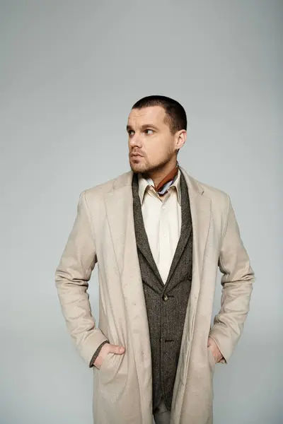 A man in a stylish coat stands with his hands in his pockets, looking off to the side. — Stock Photo