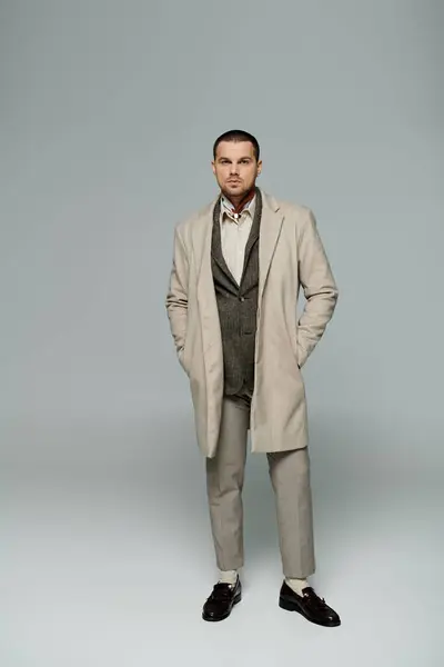 Man in beige coat and pants, brown loafers, stands before white backdrop. — Stock Photo