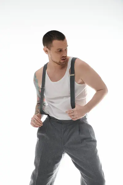 A stylish man in a white tank top and grey trousers, looking over his shoulder. — Stock Photo