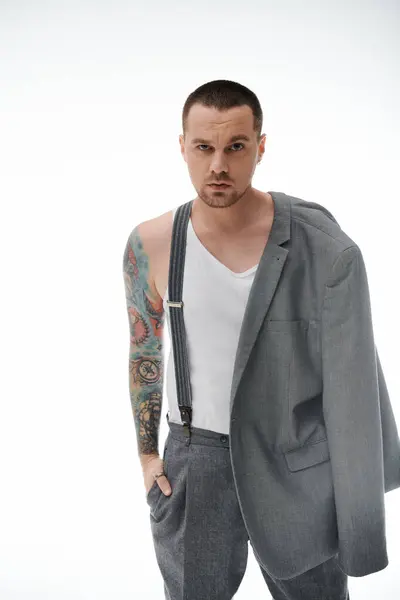 A stylish man with a tattooed arm stands confidently, wearing suspenders and a white tank top. — Stock Photo