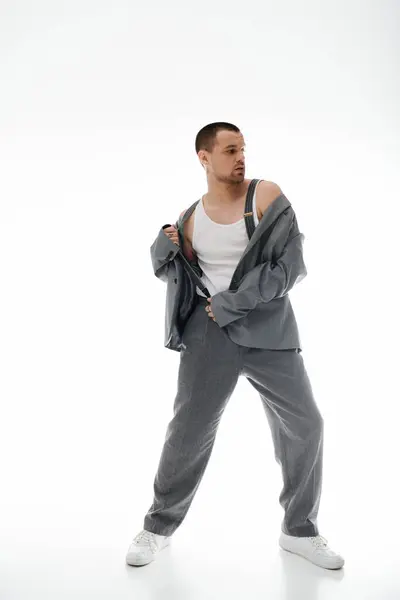 A man poses in a studio, adjusting his jacket with a confident air. — Stock Photo