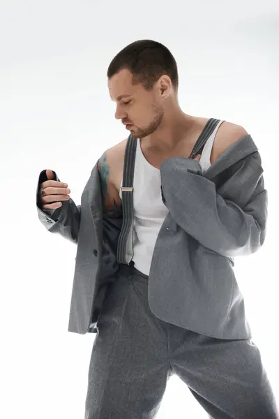 Un hombre vestido con estilo posa en un ambiente de estudio, vistiendo un traje gris y camiseta blanca. — Stock Photo