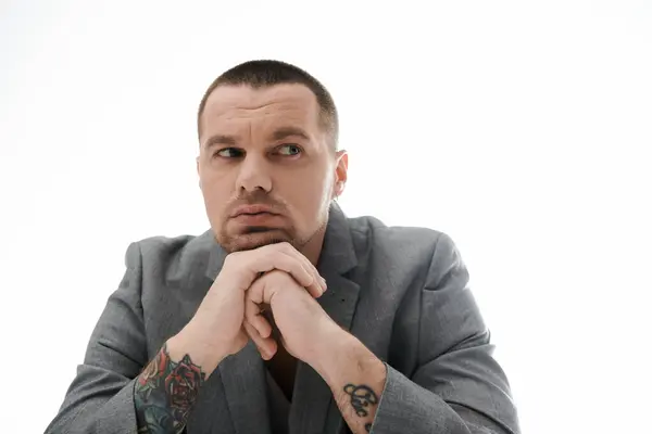 A man in a grey suit rests his chin on his hand, lost in thought. — Stock Photo