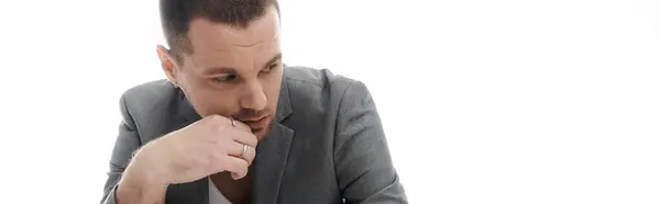 A stylish man in a blazer ponders in a white studio space. — Stock Photo