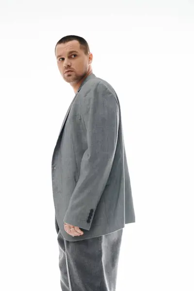 A stylish man in a grey suit looks over his shoulder. — Stock Photo