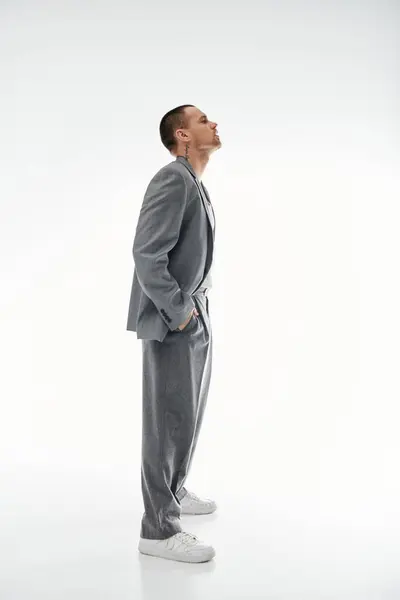 A stylishly dressed man in a grey suit stands in profile, looking up at something unseen. — Stock Photo