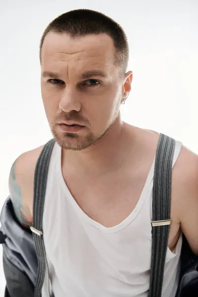 A man with a stylishly short haircut and a white tank top stares intensely at the camera. — Stock Photo