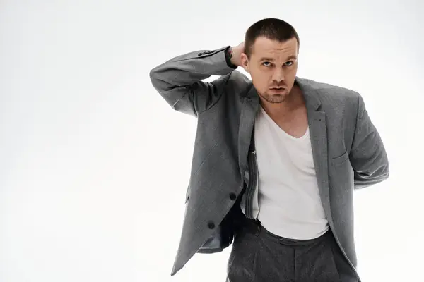 A stylish man in a grey blazer and white t-shirt poses against a white background. — Stock Photo