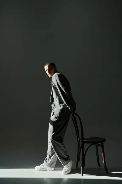 Un homme en costume gris passe devant une chaise en bois. — Photo de stock