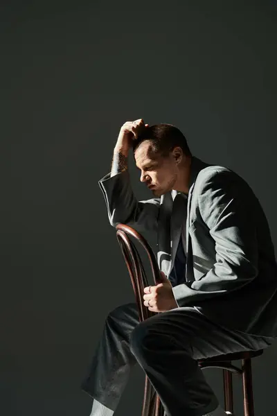 A man in a suit sits thoughtfully on a chair, lost in thought. — Stock Photo