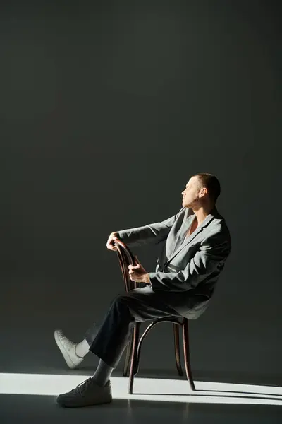 A man in a grey suit sits on a chair, bathed in light. — Stock Photo