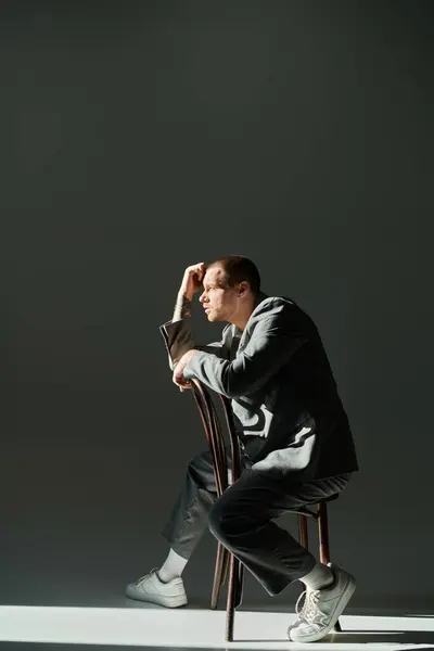 A man in a stylish gray suit sits thoughtfully on a chair, lost in thought. — Stock Photo