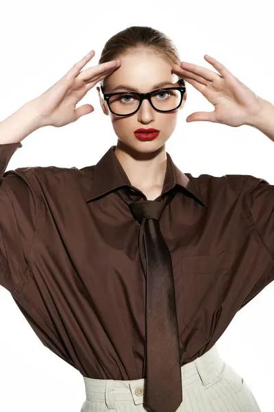 A young woman in a brown button-down shirt and tie, poses with her hands on her face. — Stock Photo