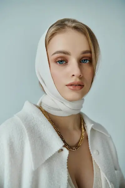 Una donna in una sciarpa testa bianca e maglione bianco guarda direttamente la fotocamera. — Foto stock