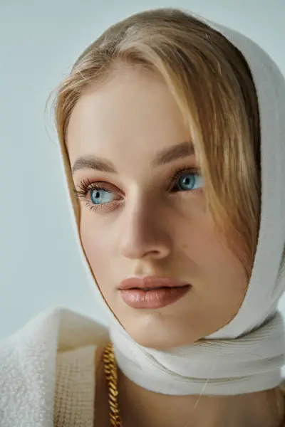 A young woman with blonde hair wears a white scarf and gazes thoughtfully off-camera. — Stock Photo