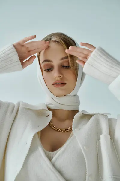 Una donna in abito bianco lavorato a maglia e sciarpa posa con un'espressione contemplativa. — Stock Photo