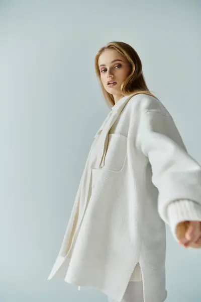 A woman in a white coat looks over her shoulder at the camera. — Stock Photo