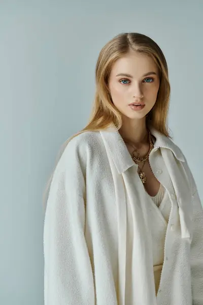 Uma jovem com longos cabelos loiros em um elegante suéter branco olha para a câmera. — Fotografia de Stock