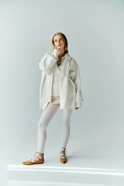 A young woman in a white ensemble ponders, bathed in soft light. — Stock Photo