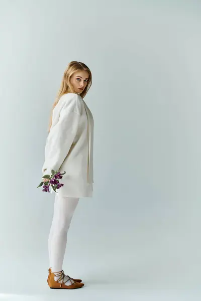 Mujer joven en vestido blanco con ramo púrpura sobre fondo blanco. - foto de stock
