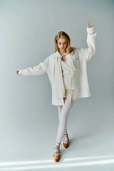 A young woman in a white outfit poses with one arm raised in a studio setting. — Stock Photo