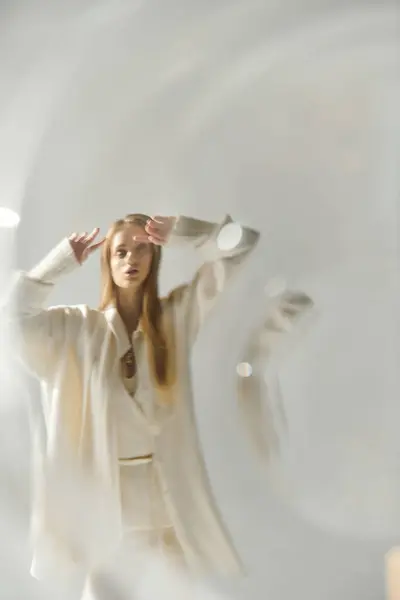 Young woman in white outfit stands against white background, arms raised. — Stock Photo