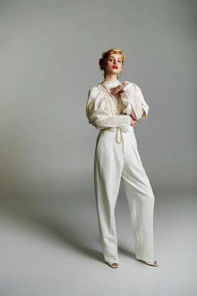 Une femme en pantalon blanc et un chemisier se tiennent en confiance dans un cadre de studio. — Photo de stock
