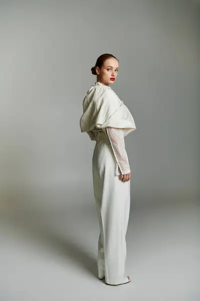 Une femme pose dans une tenue blanche chic sur fond gris. — Photo de stock