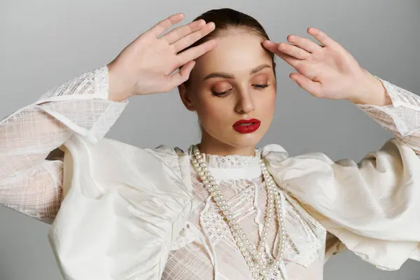 Mujer en blusa de encaje blanco, collar de perlas, miradas hacia abajo, manos en la frente. — Stock Photo