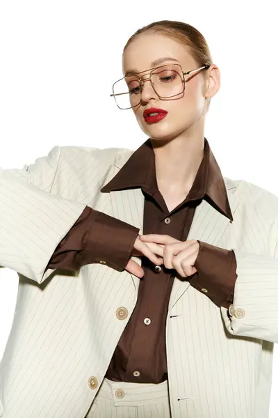 A young woman in a white pinstripe suit adjusts the cuffs of her brown shirt. — Stock Photo