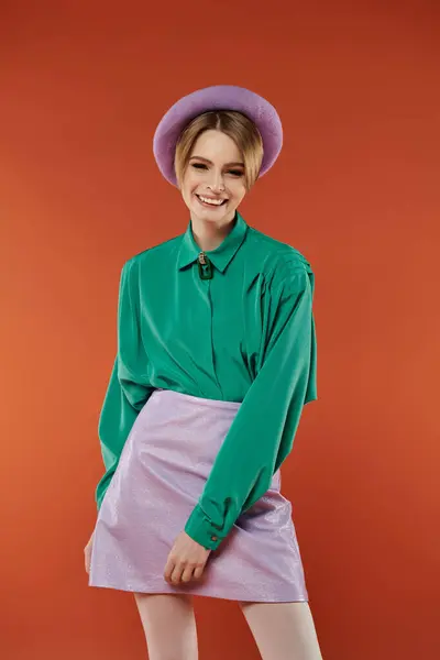 Uma mulher em uma camisa verde e saia roxa sorri enquanto posando. — Fotografia de Stock