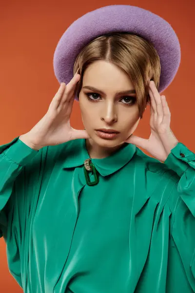 Elegante giovane donna in stile grunge posa con fiducia in cappello viola e camicia verde. — Foto stock