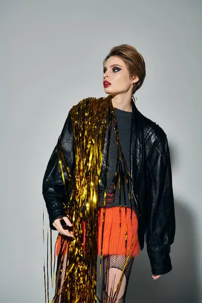 A woman in a leather jacket and fishnet stockings poses with golden confetti. — Stock Photo