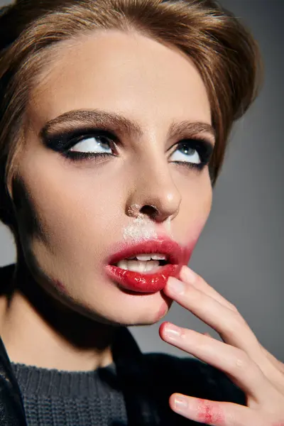 A woman with messy, dark makeup and red lipstick gazes upwards, her finger tracing her lips. — Stock Photo
