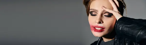 A woman with smudged lipstick poses against a gray backdrop. — Stock Photo