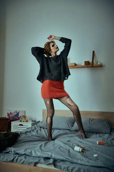 A stylish woman poses on a bed in a grungy bedroom. — Stock Photo