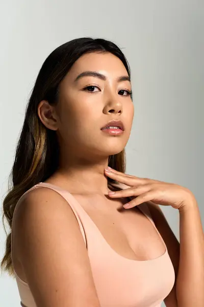 A woman in a peach tank top rests her hand against her neck. — Stock Photo