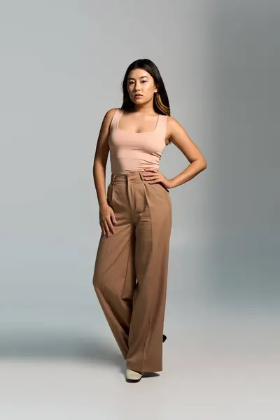 A woman in stylish attire stands in a studio setting. — Stock Photo