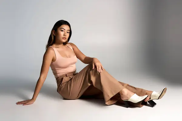 Jeune femme assise dans une pose détendue, tenue élégante mise en valeur par son regard. — Photo de stock