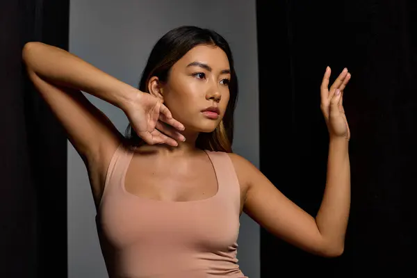 A young woman in a simple tank top poses with her arm extended, catching the soft light. — Stock Photo