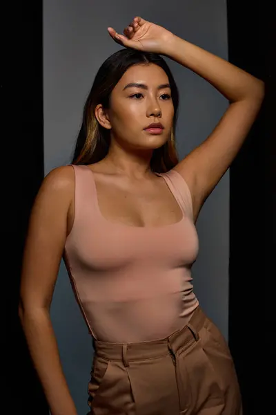 Woman with long hair, sleeveless top, khaki pants poses against neutral backdrop — Stock Photo