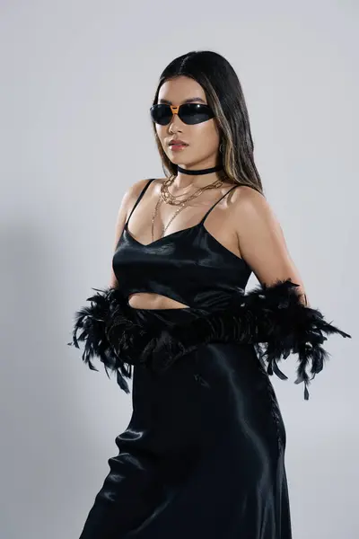 Stylish woman in black dress, dramatic feathered sleeves, poses confidently. — Stock Photo