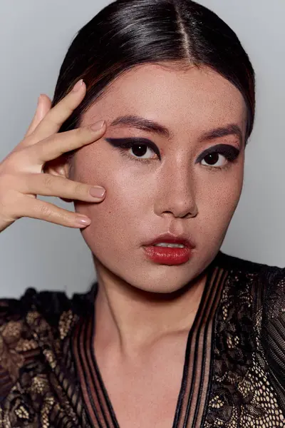 Une femme asiatique, portant une robe en dentelle noire, regarde directement la caméra. — Photo de stock