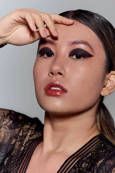 Une femme avec un eye-liner foncé et un soupçon de rouge à lèvres regarde directement la caméra. — Photo de stock