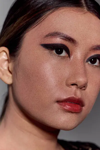 Close-up portrait of an Asian woman with striking black eyeliner and a hint of red lipstick. — Stock Photo