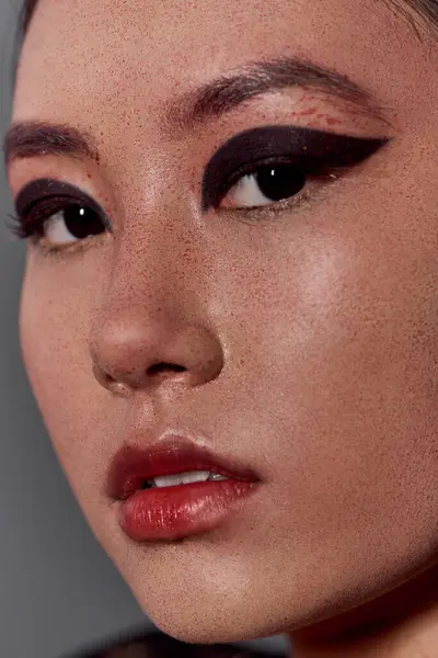 A close-up portrait of a woman's face, highlighting her striking dark eyes and bold red lips. — Stock Photo