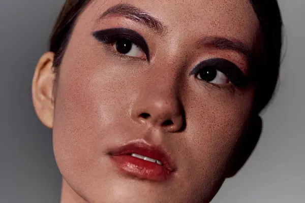 Une femme avec un eye-liner noir saisissant regarde légèrement vers le haut. — Photo de stock